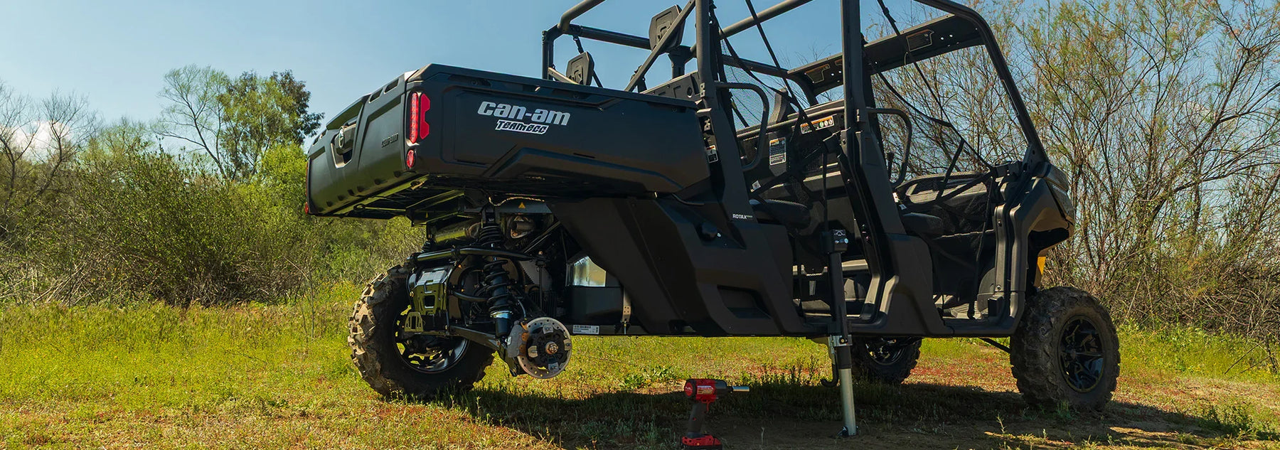 Utility vehicle with Can-Am branding being lifted by AGM  Manual Jack Sport in a grassy outdoor setting