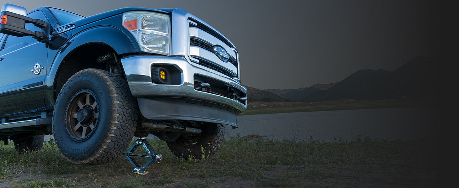 Black Ford F-350 being lifted by an AGM Scissor Jack HD next to a lake