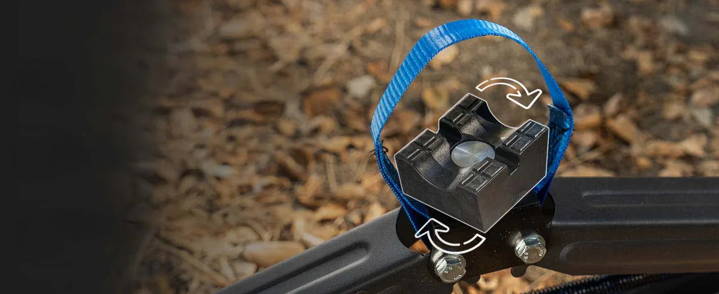 Close-up of the AGM Scissor Jack 4-in-1 combo head with a blue carry handle, shown outdoors against a blurred background of dry leaves and mulch. White arrows are overlaid near the top indicating a rotation feature.