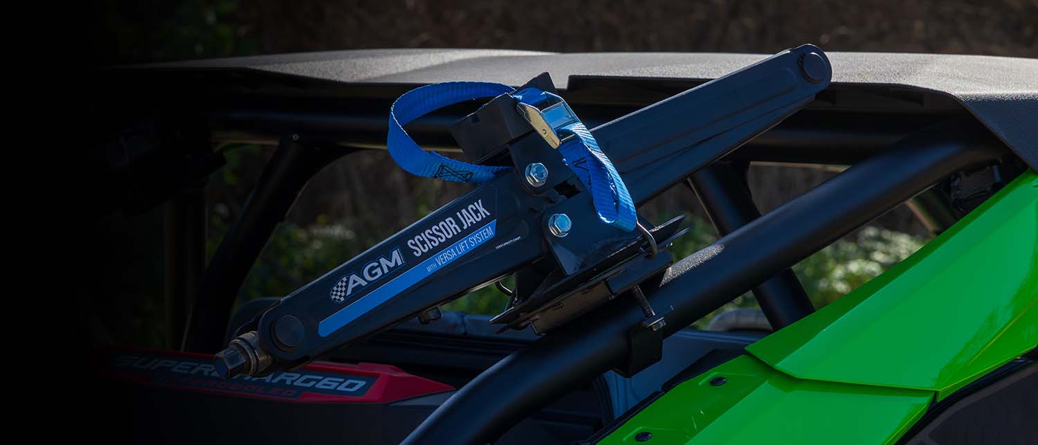 Close-up of an AGM Scissor Jack resting in an AGM Scissor Jack Mount installed on the roll cage of a green and black off-road vehicle.